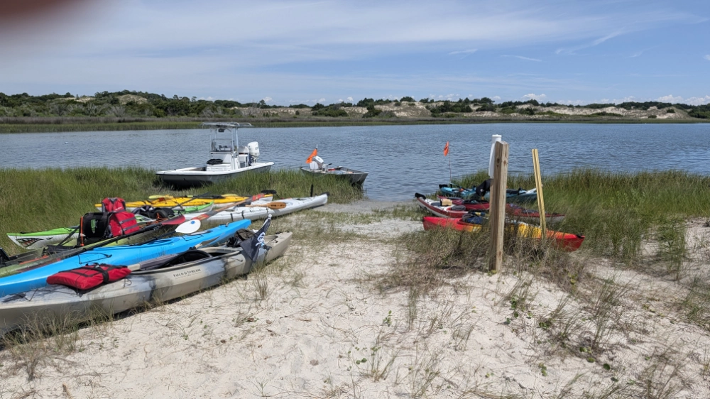 Multiple kayaks and  a small boat at the kayak launch/landing area at Bear Island