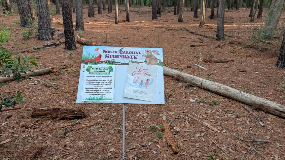A stand along the Live Oak Trail at Hammocks Beach State Park that holds a page of a book and an introductory page to the Storybook Trail